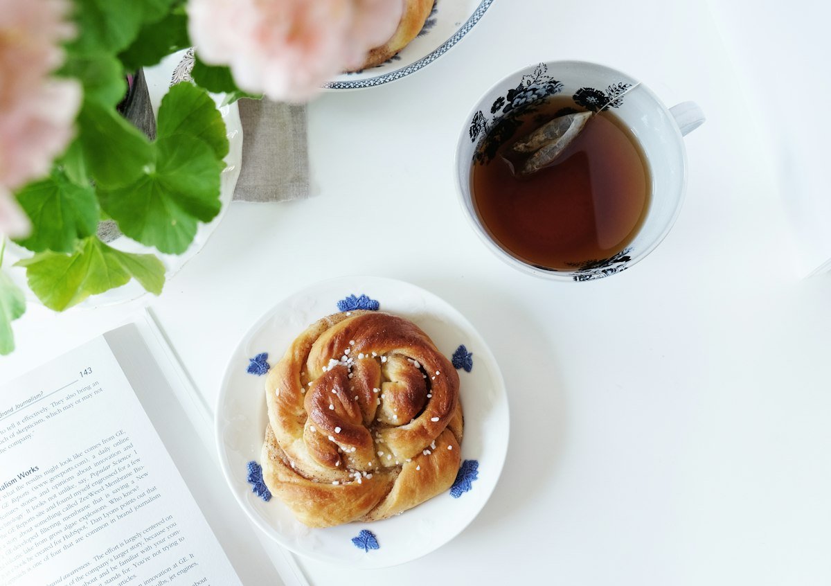 Coffee and a cinnamon bun on a white table