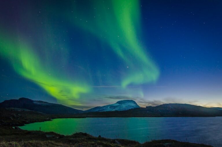 Northern lights over mountains and a lake in Swedish Lapland
