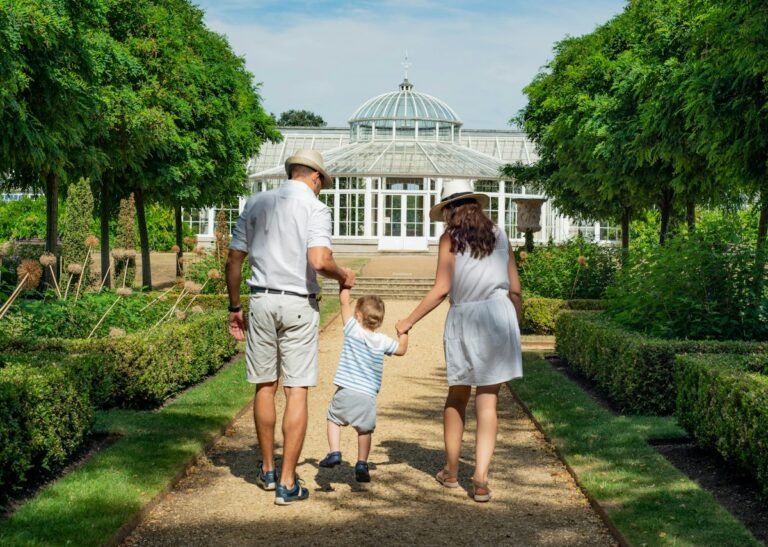 Parents walking hand in hand with their child through a garden