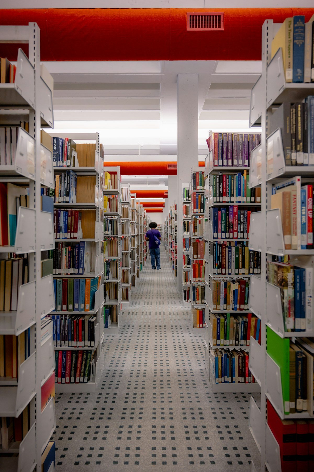 Student walking through a library filled with books